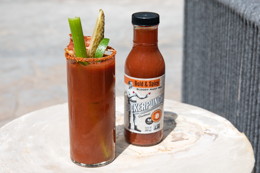 A glass of Bloody Mary cocktail next to a bottle of SuckerPunch Bloody Mary Mix